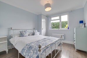 Une chambre à coucher avec un lit, des tables de chevet, une fenêtre et un radiateur.
