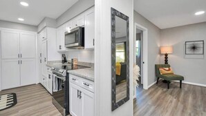 A modern kitchen with white cabinetry, a built-in microwave, and a stainless steel range hood. - 4 BR Luxury Home in Friendswood (Friendswood)