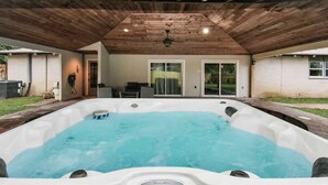 A hot tub under a wooden roof with a view of a house and a grassy yard. - 4 BR Luxury Home in Friendswood (Friendswood)
