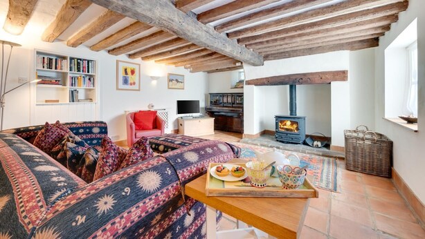 A cozy living room with exposed wooden beams, a fireplace, a sofa set, a bookshelf, and a television. - 2 Bed in Walsham-le-Willows (oc-gabpla) (Walsham le Willows)