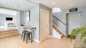 A modern interior with a kitchen area, a dining table with stools, a staircase, and an exit sign. - 1 Bed in Newburgh (oc-h32593) (Newburgh)