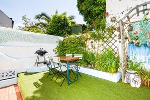 A patio with artificial grass, a barbecue grill, and a table with chairs. - 3 Bed in Newquay (oc-p00484) (Newquay)