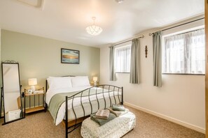 A bedroom with a bed, bedside tables, a nightstand, a mirror, a window with curtains, and a painting on the wall. - 3 Bed in Little Ellingham (oc-2147) (Little Ellingham)