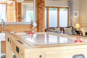 A wooden indoor table with a smooth, reflective surface and red game pieces, set in a room with wooden walls and a large mirror. - 3 Bed in Wadebridge (oc-p00104) (Little Petherick)