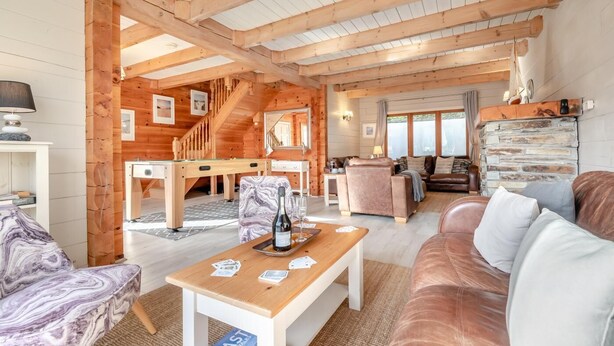 Un'ampia zona giorno con travi in legno, tavolo da biliardo, divano e tavolo da pranzo.