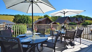 Una terrazza con posti a sedere all'aperto, comprensivi di tavoli e sedie, e due grandi ombrelloni per l'ombra.