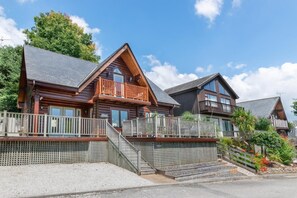 A row of log cabins with balconies, wooden railings, and a gravel driveway. - 3 Bed in Wadebridge (oc-p00104) (Little Petherick)