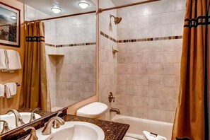 Ein Badezimmer mit Waschbecken, Spiegel, Dusche und Toilette.