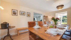 A dining area with a wooden table set for four, chairs, a bench, a small table with a pot, and framed pictures on the wall. - 4 Bed in Welshpool (oc-wab267) (Welshpool)