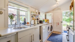Una cocina moderna con lavadora integrada, un lavabo y un ventanal con vistas al exterior.