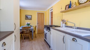 A compact kitchen with a stove, sink, and dining area. - 2 Bed in Cromer (oc-t32572) (Cromer)