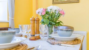 A dining table set with plates, bowls, glasses, and cutlery, accompanied by a vase of flowers and salt and pepper shakers. - 2 Bed in Cromer (oc-t32572) (Cromer)