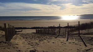 Una platja amb una tanca de fusta, terreny sorrenc i l'oceà al fons.