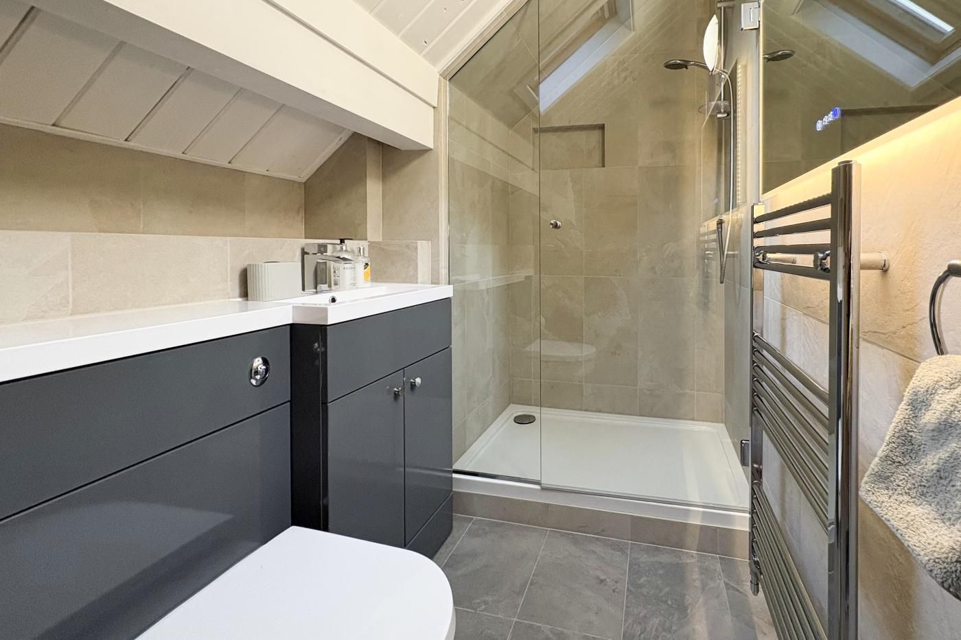 Une salle de bain moderne équipée d’une douche, de toilettes et d’un meuble-lavabo.