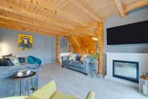 A wooden interior with a sofa, a small table, a TV, and a fireplace.