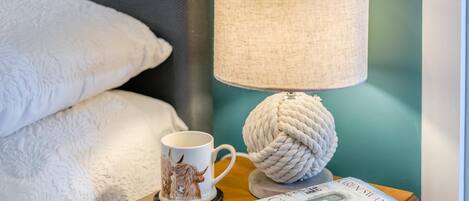 Ein Nachttisch mit einer Lampe, einer Tasse und einem Buch.
