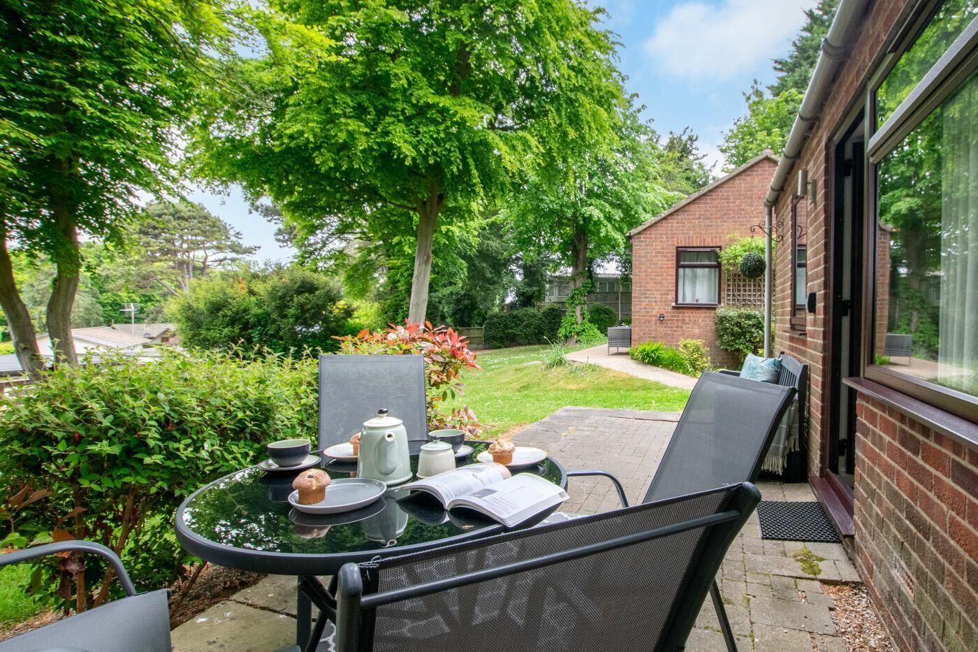 A patio with a round table, two chairs, and a brick building in the background.