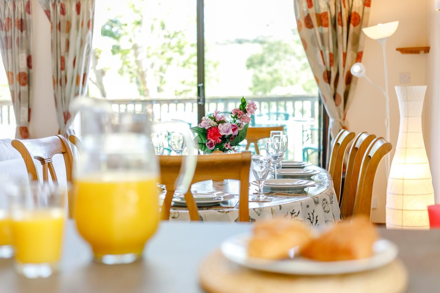 A breakfast table set with plates, glasses, and a pitcher of orange juice.