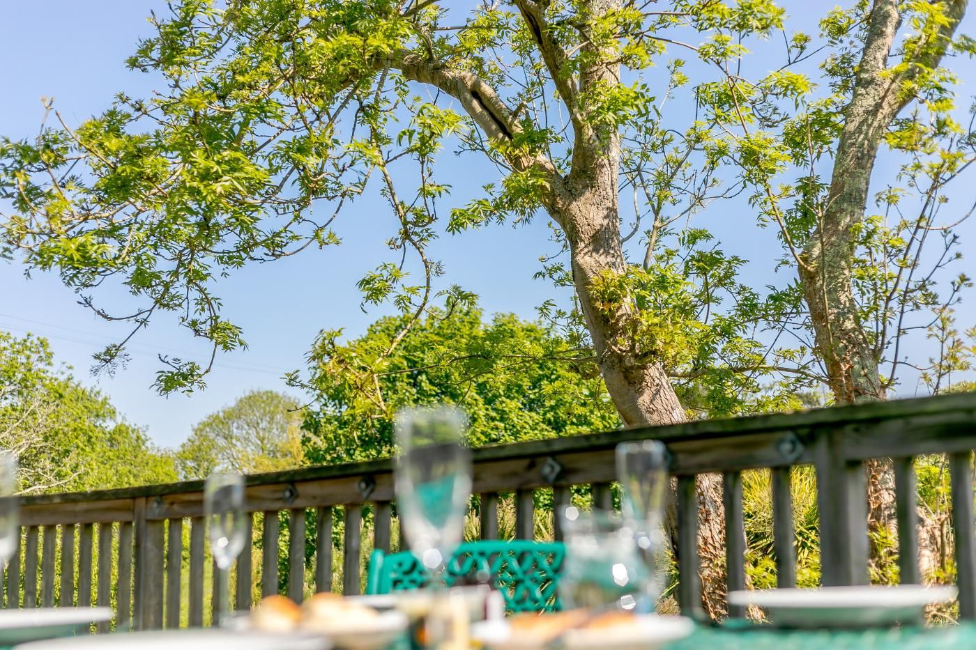 Een eetruimte met uitzicht op bomen en een houten balustrade.