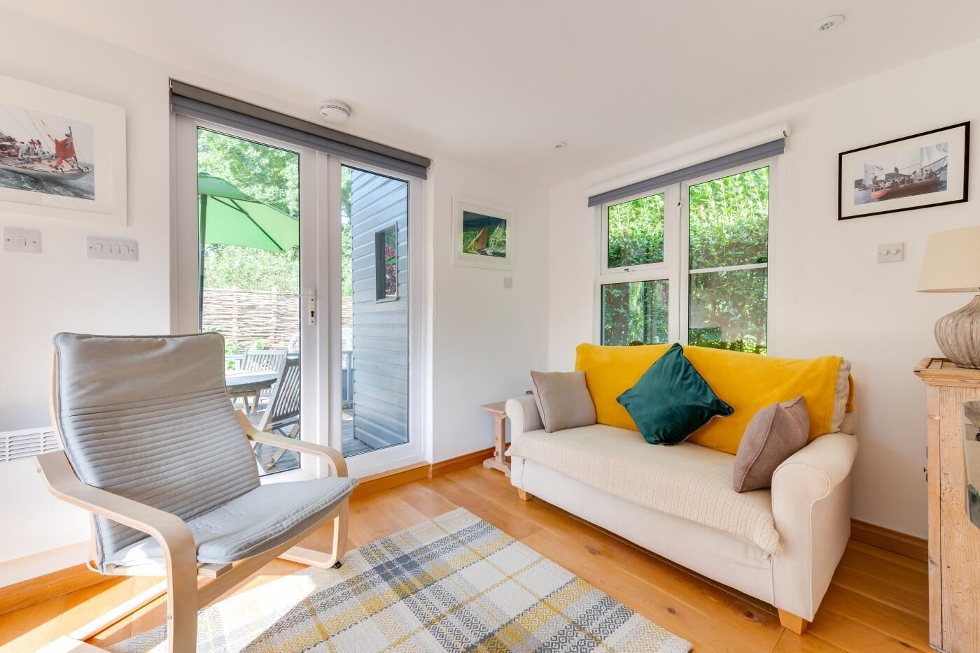 A cozy living room with a sofa, a chair, and a view through large windows.