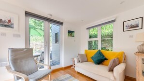 A cozy living room with a sofa, a chair, and a view through large windows.