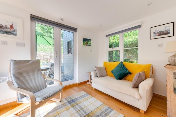 A cozy living room with a sofa, a chair, and a view through large windows.