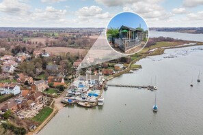 An aerial view of a riverside village with a marina, houses, and a small dock.