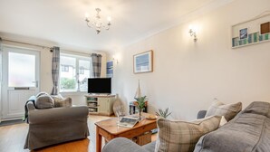 A living room with a sofa set, a coffee table, a television, and a window with curtains.