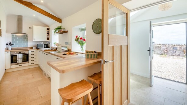 Een moderne keuken met houten kastjes, een ingebouwde oven en een groot raam.