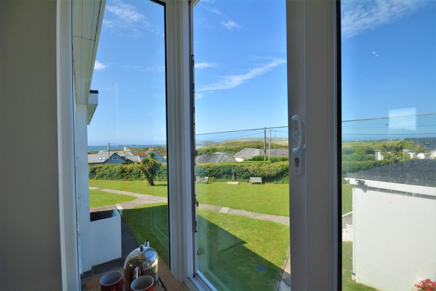 A room with a large window offering a view of a green landscape and houses.