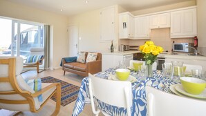 Een moderne keuken met witte kastjes, een eettafel gedekt met gele borden, en uitzicht buiten door een schuifdeur.