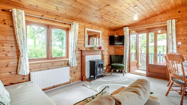A cozy cabin interior with wooden walls, a fireplace, a sofa, and a dining area.