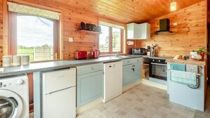 A compact kitchen with wooden walls, a built-in oven, a sink, and a dishwasher.