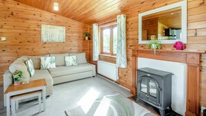 A cozy cabin interior with a sofa, a small table, a fireplace, and a mirror on the wall.