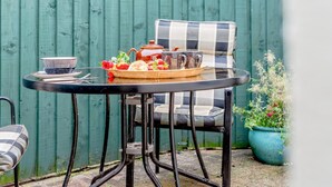 A round table with a checkered chair, a tray with food and drinks, and a potted plant. - 1 Bed in Wadebridge (oc-p00232) (Wadebridge)