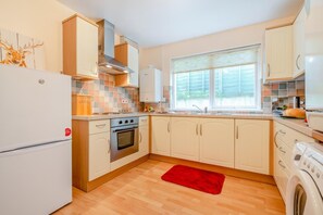 A compact kitchen with a refrigerator, oven, and washing machine.