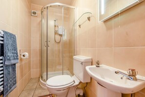 Une salle de bain avec une douche à parois de verre, des toilettes et un lavabo.