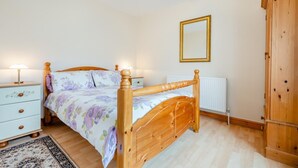 A bedroom with a wooden bed, a nightstand, a dresser, a radiator, and a wardrobe. - 1 Bed in Wadebridge (oc-p00232) (Wadebridge)