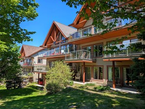 A multi-story hotel with balconies, a stone facade, and a well-maintained lawn.