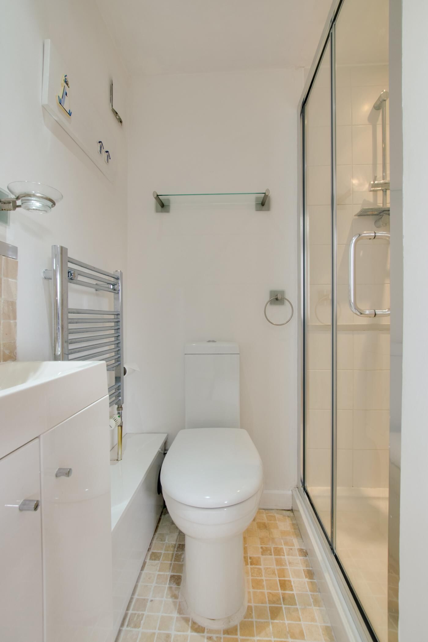A modern bathroom with a toilet, a glass shower enclosure, and a white sink.