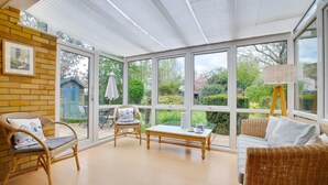 A conservatory with wicker furniture, a table, and a view of the garden. - 4 Bed in Reydon (oc-fll) (Reydon)