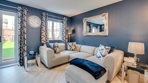 A modern living room with a sectional sofa, a large mirror, and a glass coffee table. - 2 Bed in Whitby (oc-w1008) (Whitby)