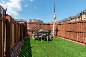 A backyard with a wooden fence, a table with chairs, and artificial grass. - 2 Bed in Whitby (oc-w1008) (Whitby)