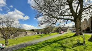 A grassy area with a paved path, a large tree, and a building in the background. - 3 Bed in Bainbridge (oc-ds1026) (Bainbridge)