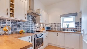 A modern kitchen with white cabinets, a wooden countertop, a built-in oven, and a microwave. - 3 Bed in Bainbridge (oc-ds1026) (Bainbridge)
