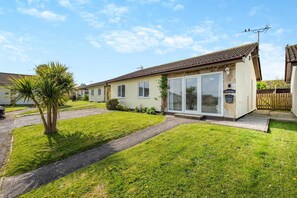 A row of single-story houses with a well-maintained lawn and a palm tree. - 3 Bed in Padstow (oc-p00131) (Saint Merryn)