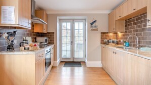 Eine moderne Küche mit Holzausstattung, integriertem Backofen, Mikrowelle und Spüle.
