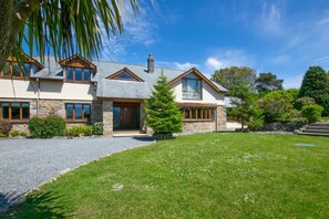 A two-story house with a stone facade, a wooden front door, and a well-maintained lawn. - 7 Bed in Ashton (oc-p00891) (Germoe)