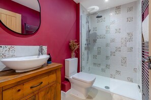 A bathroom with a white sink, wooden vanity, a toilet, and a glass-enclosed shower area. - 2 Bed in Elmswell (oc-t32377) (Elmswell)