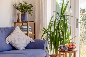 A room with a sofa, a bookshelf, a large plant, and a small table with a bowl of fruit. - 2 Bed in Elmswell (oc-t32377) (Elmswell)